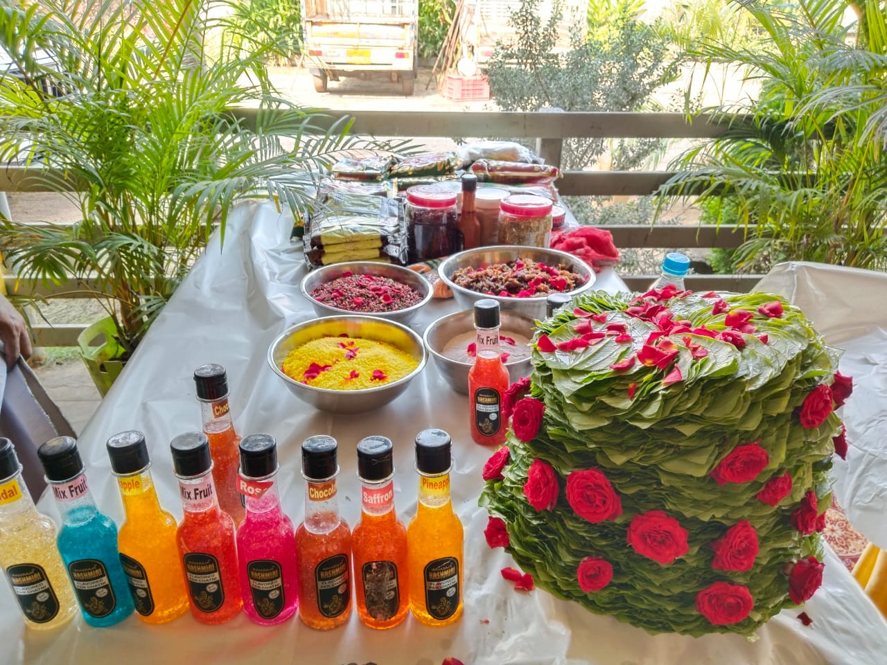 Fresh betel leaves arranged artistically with traditional paan ingredients including gulkand, supari, and fennel seeds on marble counter